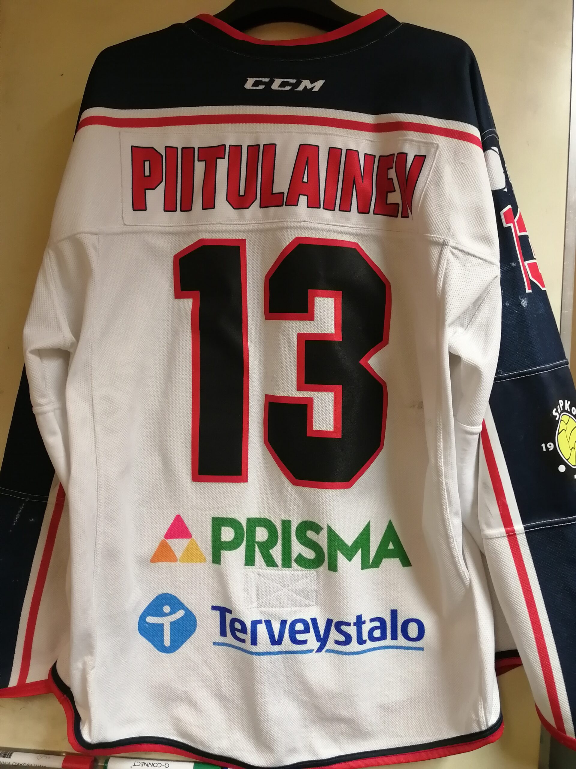 “Numero 13 selässä – pelipaita, jossa lukee työ, luotto ja lukemattomat vaihdot.”